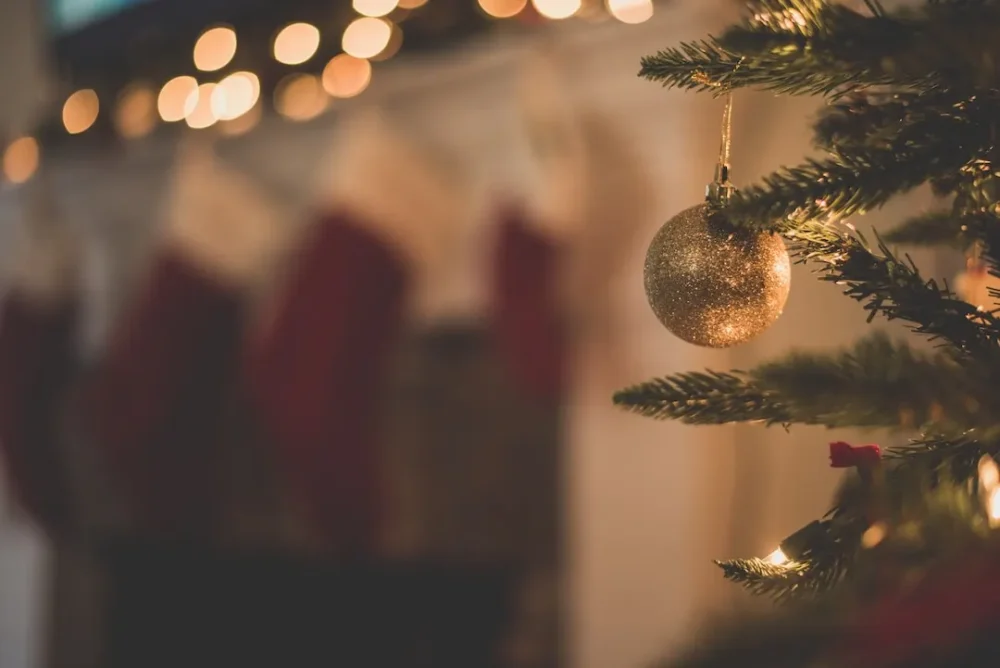 Close-up of a Christmas tree with a sparkly gold ornament hanging from one of the branches.